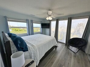 A bedroom with a bed, a chair, a remote control, and a ceiling fan. - Ocean View Apartment in Crescent Beach - 10 minutes from downtown St. Augustine. (Saint Augustine)
