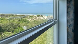 Uitzicht vanuit een raam op een strand met een heldere lucht.