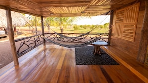 Una terraza de madera con una hamaca, una mesa y vistas a un jardín ajardinado.