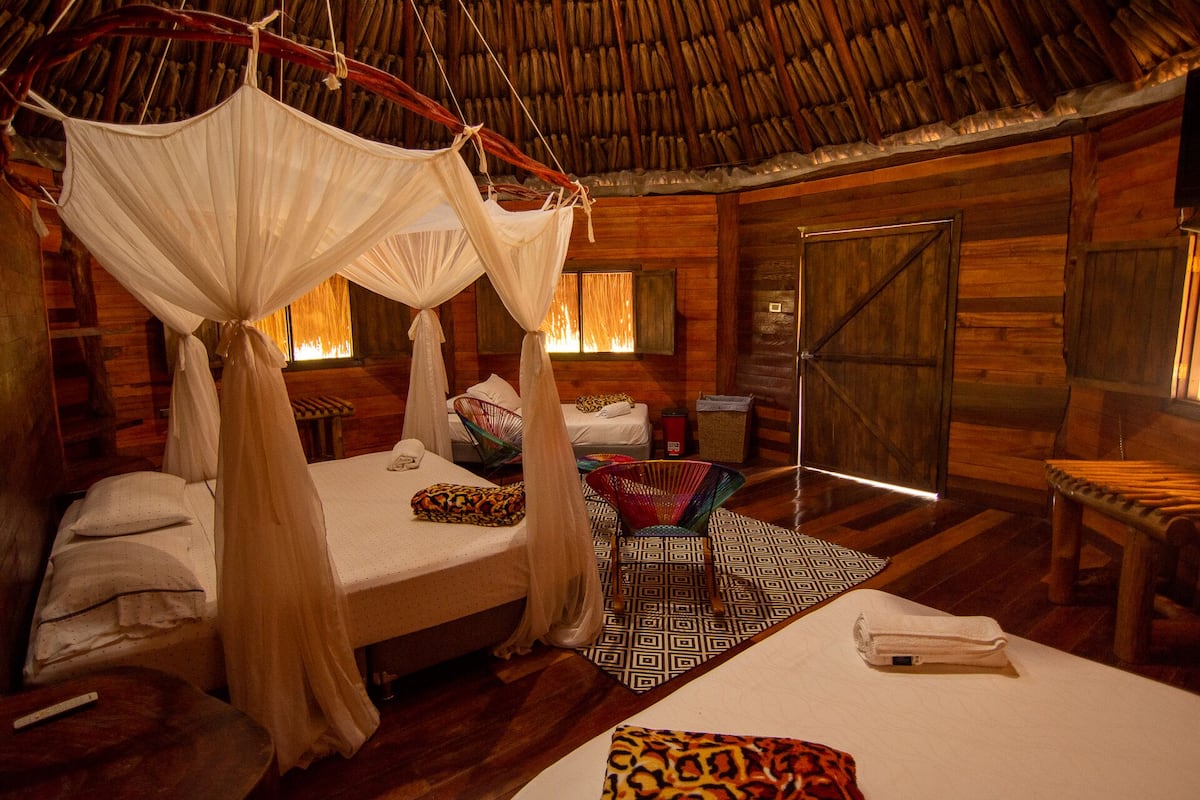 A room with a bed, a chair, and a small table. There is a door and a window.