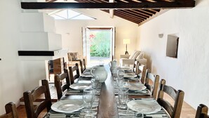 A dining table set for six with chairs, a view of the garden through a window, and a staircase leading to an upper level.