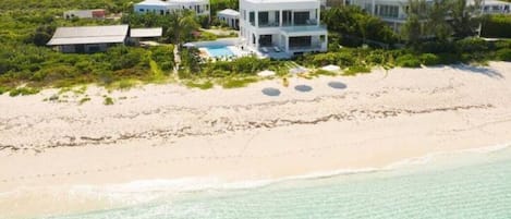 A beachfront property with multiple buildings, a pool, and a sandy beach.