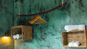 A rustic room with a teal textured wall, a wooden bed, and two wicker baskets containing rolled towels.