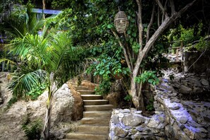 A stone staircase surrounded by lush greenery and a hanging light fixture.