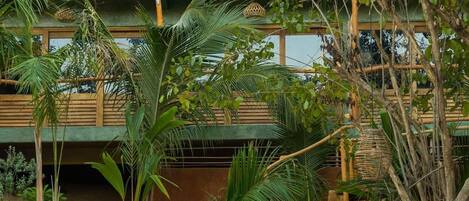 Um edifício de vários andares com telhado de palha, rodeado por vegetação exuberante e palmeiras.
