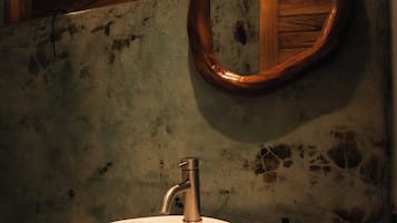 Un baño con lavamanos blanco, un espejo con marco de madera y un inodoro.