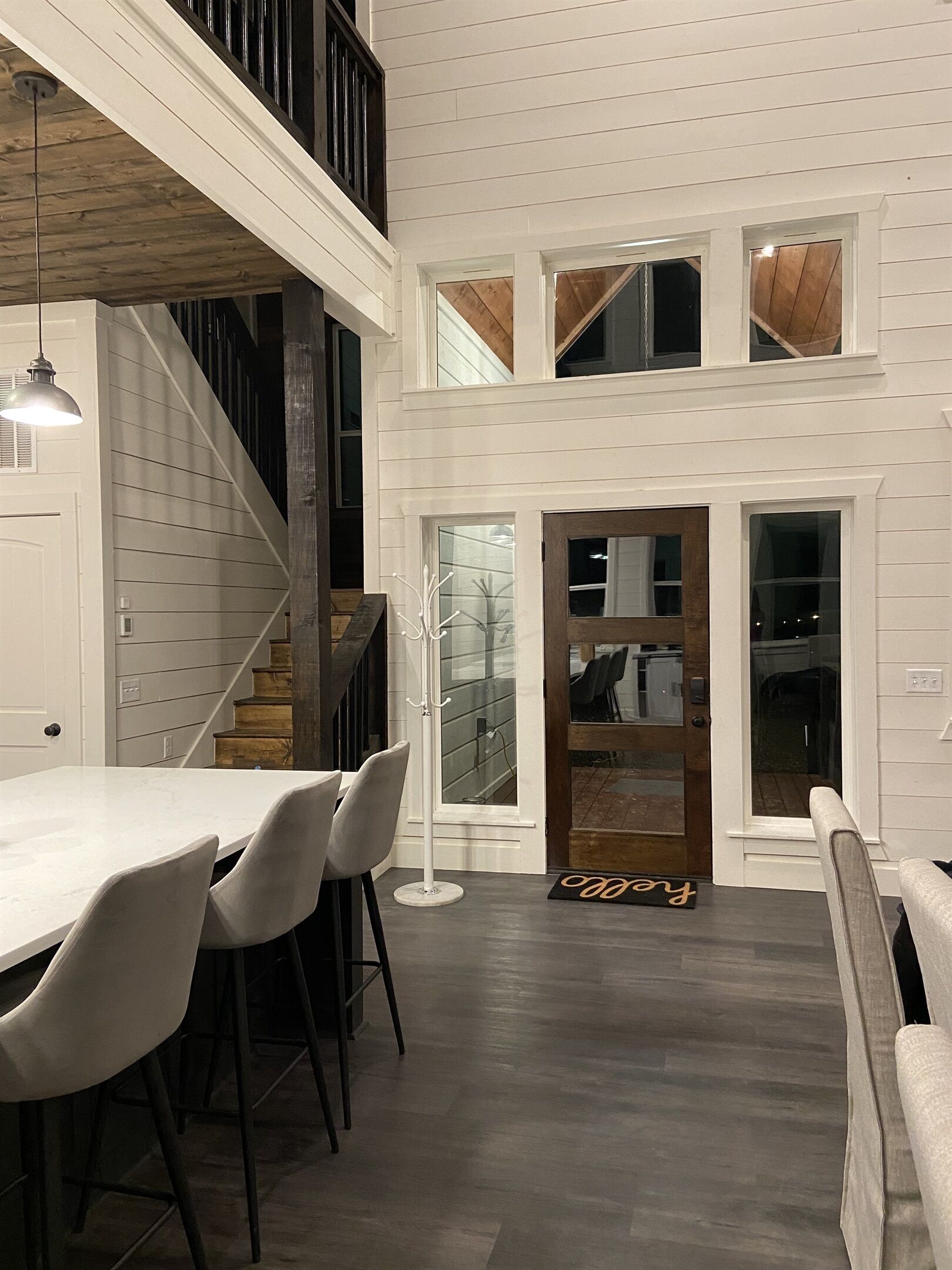 A modern interior with a dining area, a staircase, and a view to the upper level.