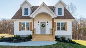 A two-story house with a central entrance, a front porch, and a front yard.
