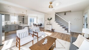 A spacious living area with a dining table, sofas, and a staircase.
