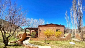 A rustic building with a patio area, surrounded by trees and a clear blue sky. - Charming 3 bedroom Ranch in scenic McElmo Canyon (Cortez)