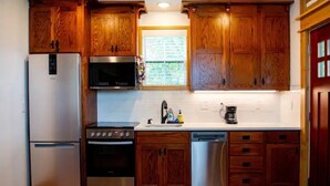 A kitchen with wooden cabinets, a refrigerator, stove, microwave, and dishwasher. - Minutes from Baum Stadium with a View! (Fayetteville)