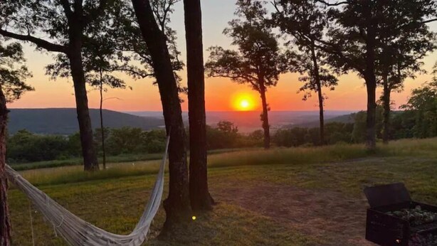 A hammock tied between trees, a picnic table, and a view of the sunset over a hilly landscape. - Minutes from Baum Stadium with a View! (Fayetteville)
