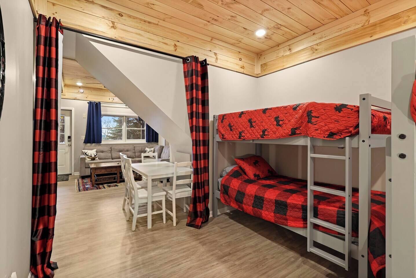 Une pièce confortable avec un lit superposé, une table à manger et un escalier menant à une autre pièce.