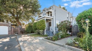 A two-story residential building with a front porch, a brick driveway, and a well-maintained garden.