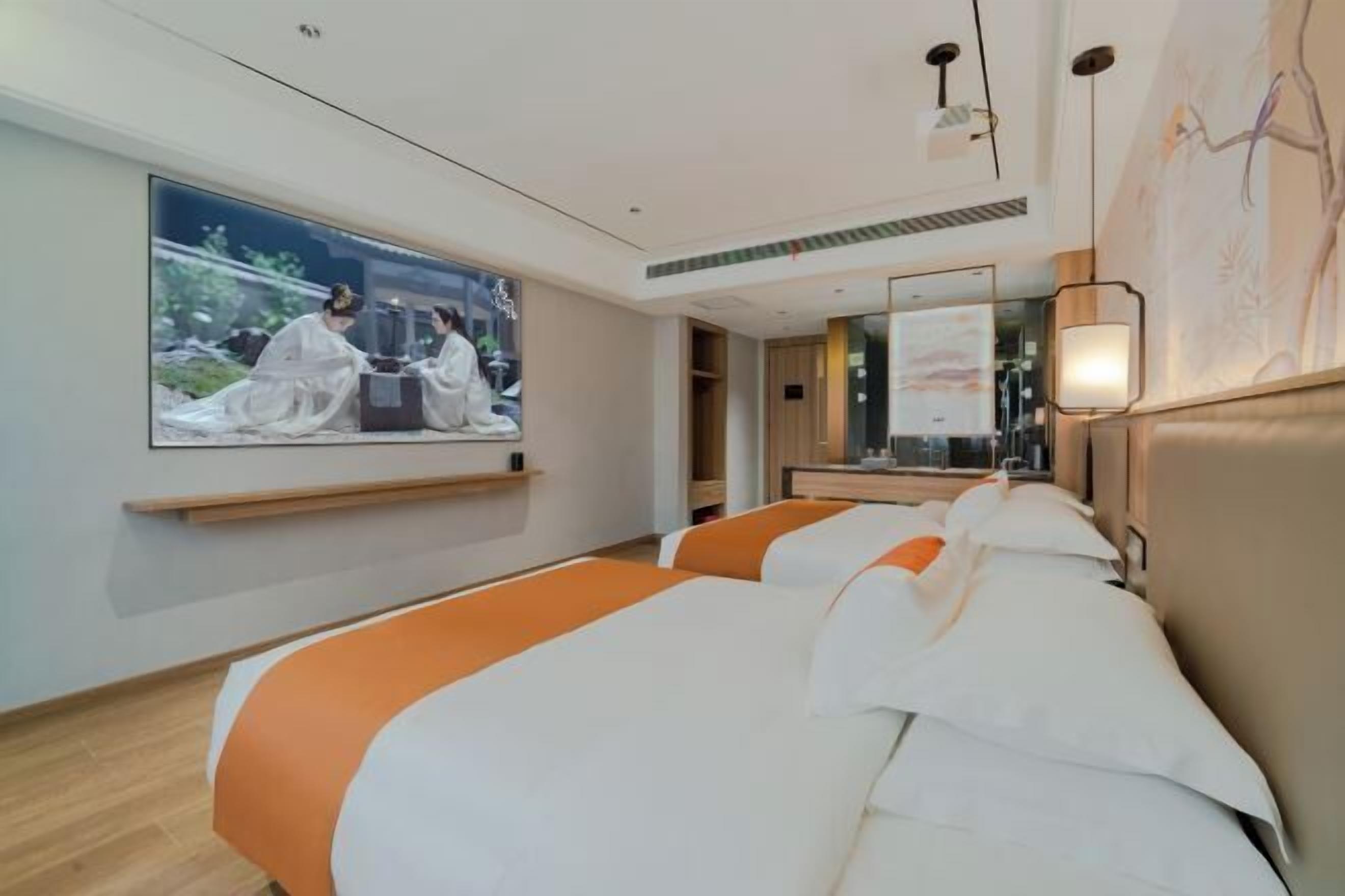A hotel room with two beds, a large TV screen, a mirror, and a wall-mounted artwork.