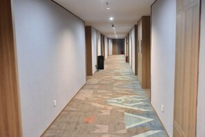 Un pasillo de hotel con alfombra estampada, paredes de madera y una larga extensión.
