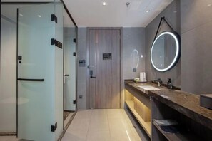 Un baño moderno con mampara de vidrio, puerta de madera, tocador con espejo e inodoro.
