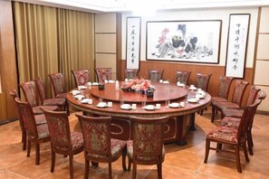 A conference room with a round table, chairs, and floral centerpieces.