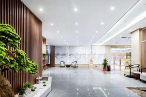 Un vestíbulo amplio con diseño moderno, que incluye una recepción, zona de estar y una gran planta.