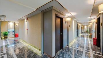 Un pasillo de hotel con suelo de mármol, puertas e iluminación empotrada en la pared.