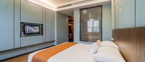 A modern hotel room with a large bed, a television mounted on the wall, and a sliding door leading to a bathroom.