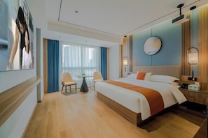 Quarto de hotel moderno com uma cama grande, uma escrivaninha, uma cadeira e vista para a cidade.