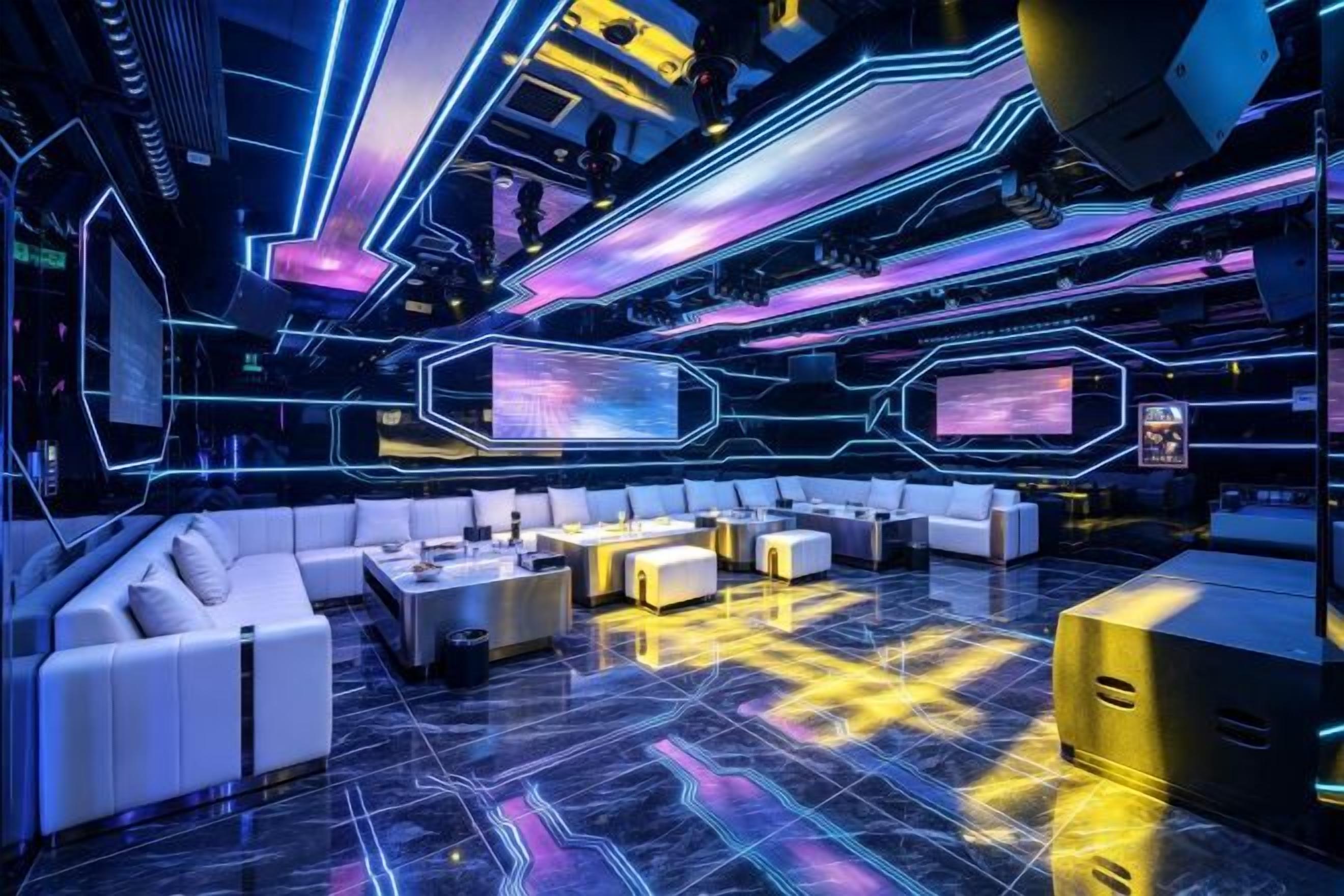 A futuristic lounge with a central seating area, neon lighting, and a large screen.