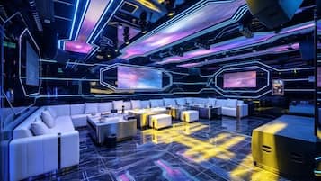 A futuristic lounge with a central seating area, neon lighting, and a large screen.