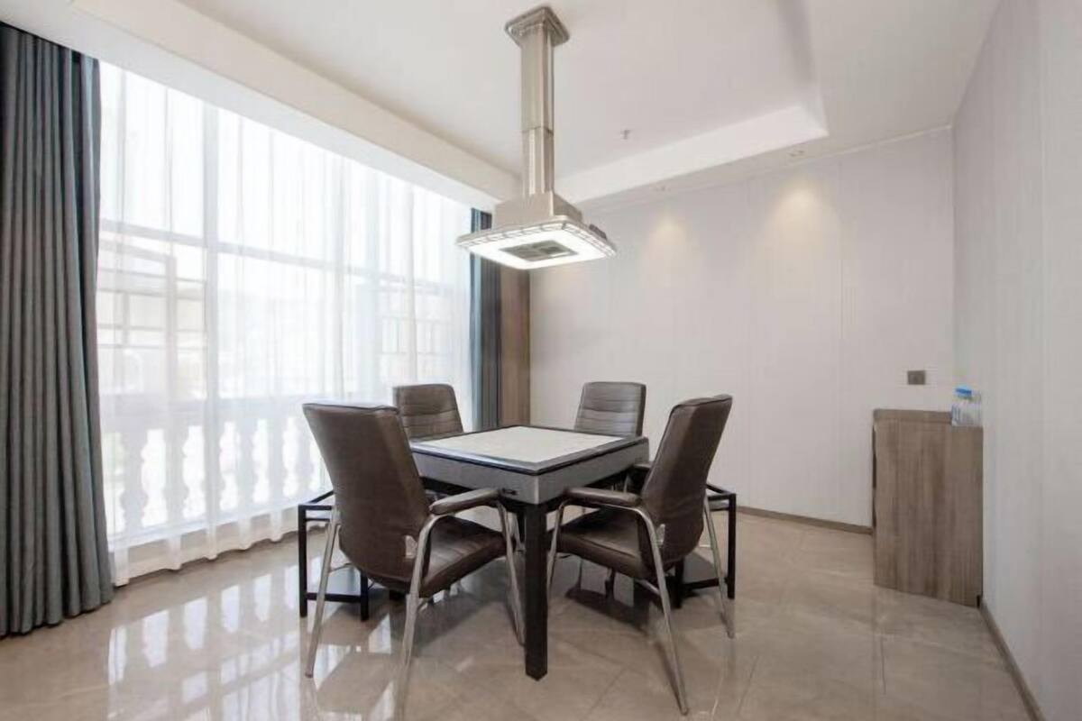 A modern dining room with a rectangular table, four chairs, a pendant light, and a view through large windows.