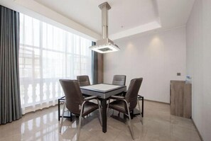 Un comedor moderno con una mesa rectangular, cuatro sillas, una lámpara colgante y vistas amplias a través de grandes ventanales.