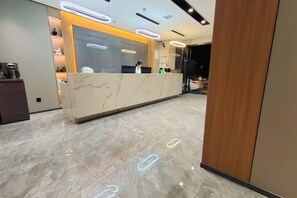 A reception desk with a marble top, a wooden panel on the right, and a modern light fixture above. - Alant Hotel (Duyun)