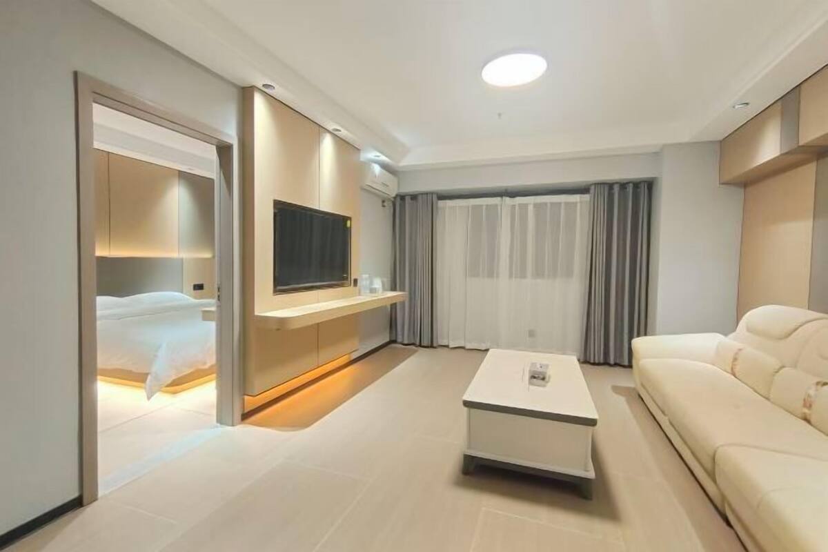 Une chambre d’hôtel moderne équipée d’un lit, d’un téléviseur à écran plat, d’un canapé et d’une table basse.