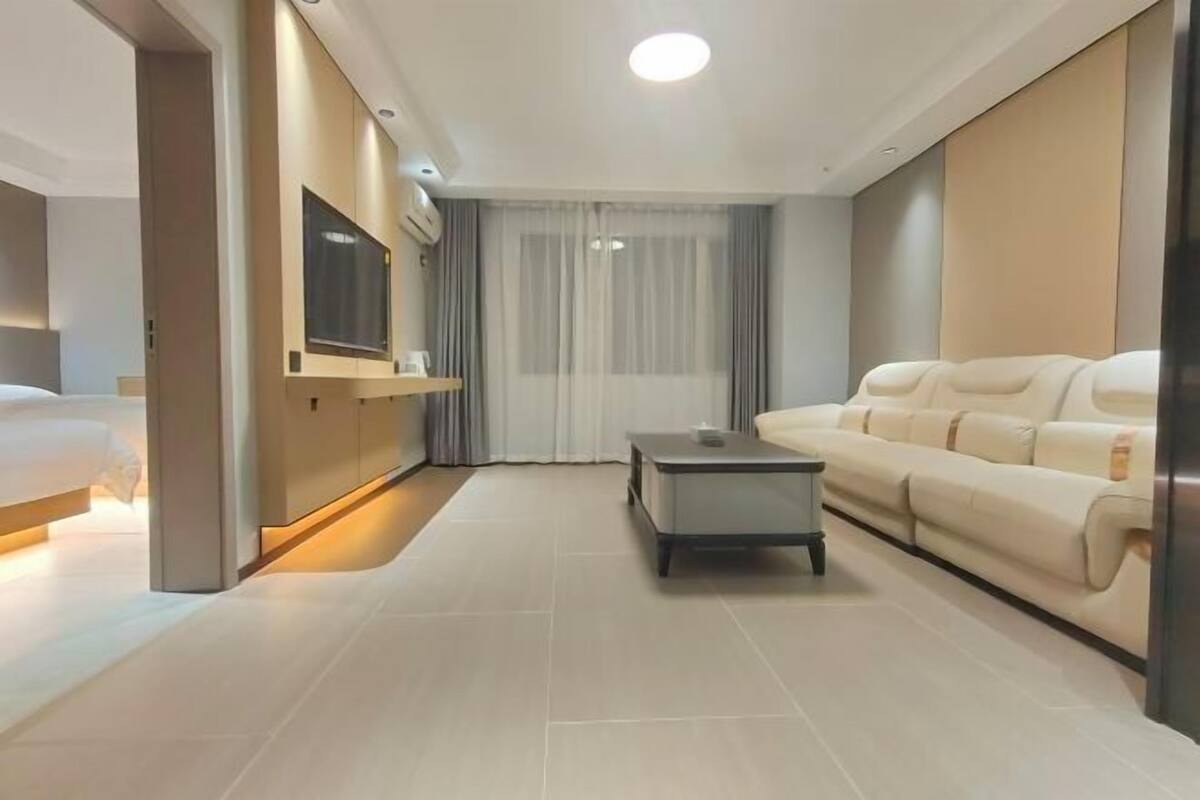 Une chambre d’hôtel moderne équipée d’un lit, d’un canapé, d’un téléviseur fixé au mur et d’une petite table.