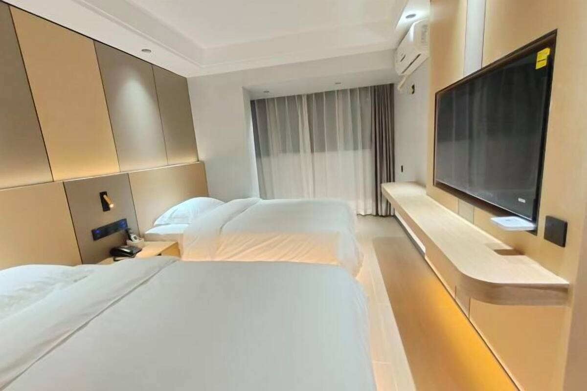 Une chambre d’hôtel avec deux lits, une télévision et un bureau.