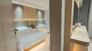 Ein modernes Hotelzimmer mit einem großen Bett, Nachttischen, einem Spiegel und einem fest installierten Schreibtisch mit Stuhl.