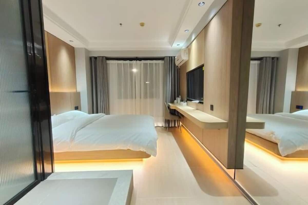 Une chambre d’hôtel avec deux lits, un grand miroir, une télévision et une table de chevet.
