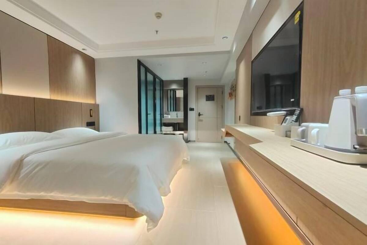 Une chambre d’hôtel moderne avec un grand lit, une table de chevet équipée d’une machine à café et un grand miroir.