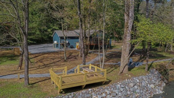 A rustic cabin with a wooden deck and a small shed in a wooded area. - Riverfront Arcade Game Room Pet Friendly Hot Tub (Ellijay)