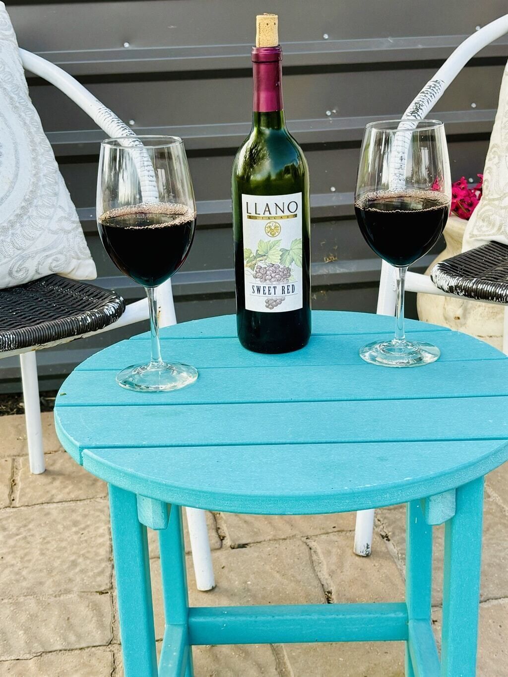 A table with two wine glasses and a bottle of Llano Sweet Red wine.