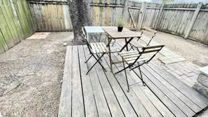 Een achtertuin met een houten terras, een tafel en stoelen.