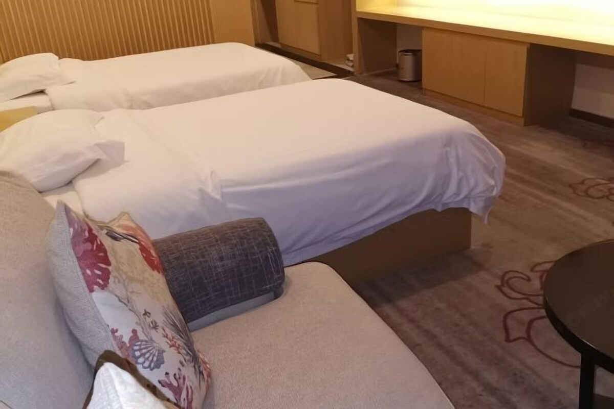 A hotel room with two single beds, a sofa, a small table, and a cabinet.