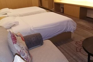 A hotel room with two single beds, a sofa, a small table, and a cabinet. - New Times Inn & Hotel (Tongchuan)