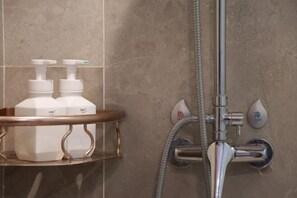 Enjoy a refreshing shower with a handheld showerhead and wall-mounted faucet in this stylish bathroom.