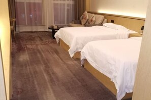 A hotel room with two beds, a small table, and a chair. - New Times Inn & Hotel (Tongchuan)