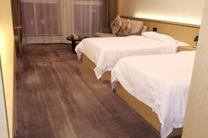 Habitación de hotel con dos camas, una mesita y una silla.