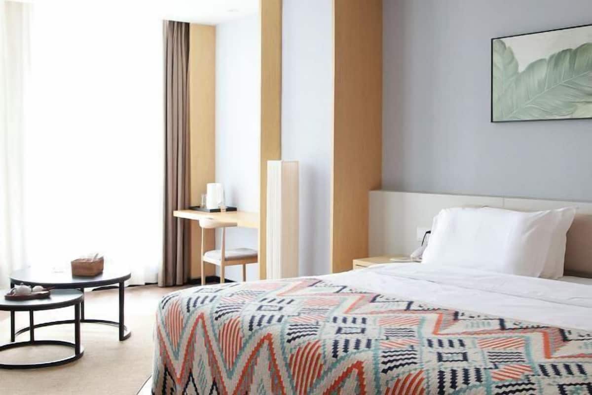 Une chambre d’hôtel avec un lit, un bureau, une chaise et une petite table.