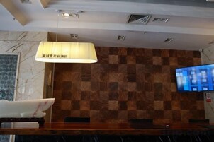 Una zona de recepción con pared de madera, un televisor y una lámpara.