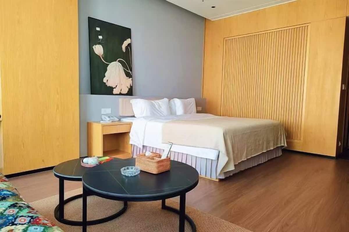 Une chambre d’hôtel avec un lit, une table de chevet et une petite table ronde sur laquelle se trouvent un panier et un verre.