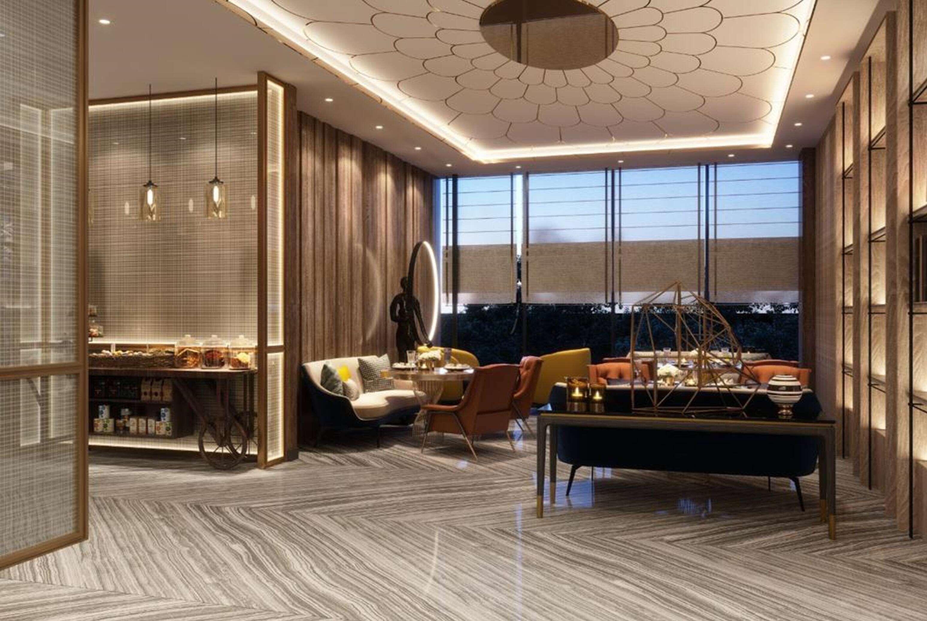 A modern hotel room with a large window, a dining area with a round table, and a seating arrangement including a sofa and chairs.