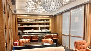 A modern interior with a sofa, chairs, a bar area, and a unique ceiling design. - Ramada Encore By Wyndham Bareilly Civil Lines (Bareilly)